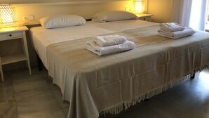 A neatly made bed with white linens and two bedside lamps.