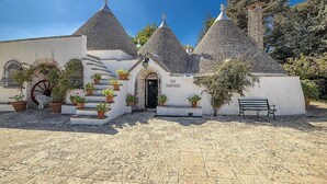 A traditional building with a white facade, multiple conical roofs, and a central staircase leading to a door.
