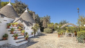 A cobblestone courtyard with a white building featuring a tiled roof and a bench.