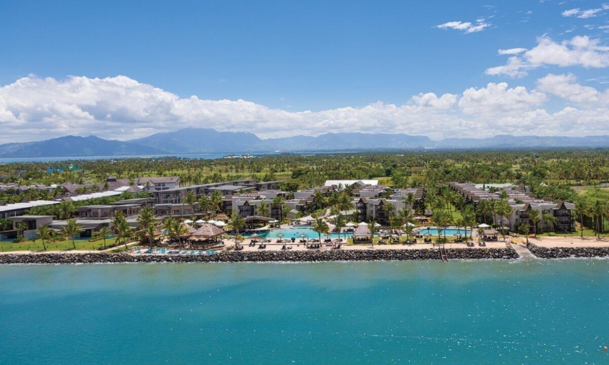Et resort med flere bygninger, en swimmingpool og udsigt til ocean og bjerge.