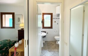 A bathroom with a toilet, sink, and window. There is a towel rack and a mirror above the sink. - La Perla di Porto Azzurro (Porto Azzurro)