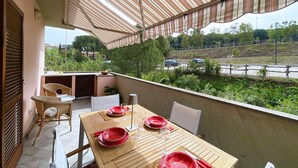 A balcony with a table set for dining, chairs, and a striped awning. - La Perla di Porto Azzurro (Porto Azzurro)