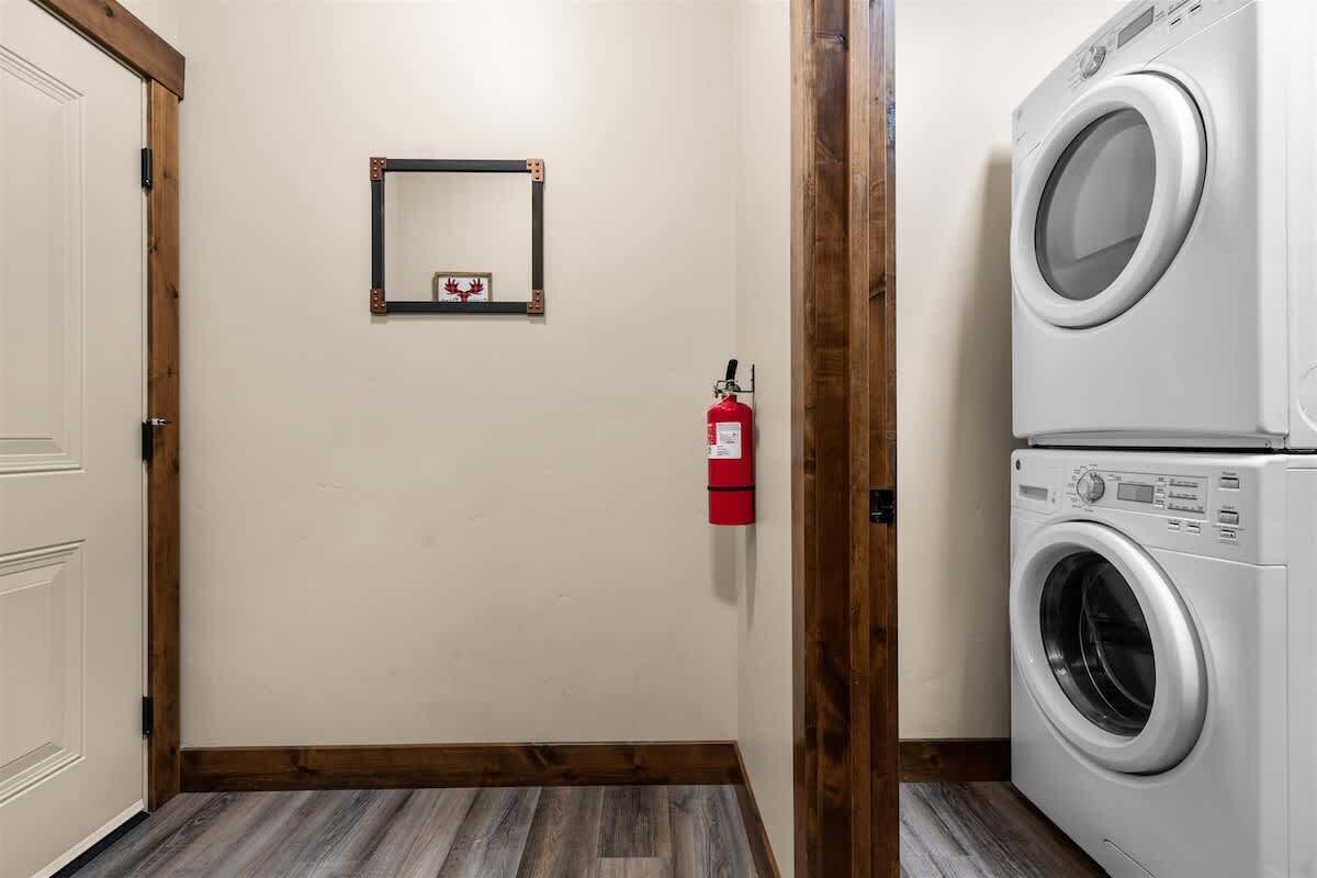 Een wasserette met een wasmachine, een brandblusser en een ingelijste foto aan de muur.