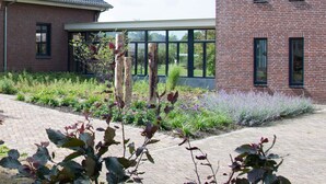 A brick building with large windows and a paved walkway. - Antonius Hoeve Chalets (Oudenbosch)