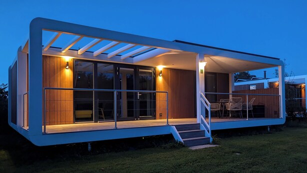 A modern house with a covered patio, large windows, and a staircase leading to the entrance. - Antonius Hoeve Chalets (Oudenbosch)