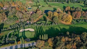 Luchtbeeld van een golfbaan met een clubhuis, zandbunkers en een vijver.