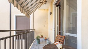 En balkon med et bord, stole og potteplanter, samt en skydedør.