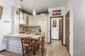 Une cuisine dotée d’un îlot central, de meubles blancs et d’un coin repas avec des chaises.