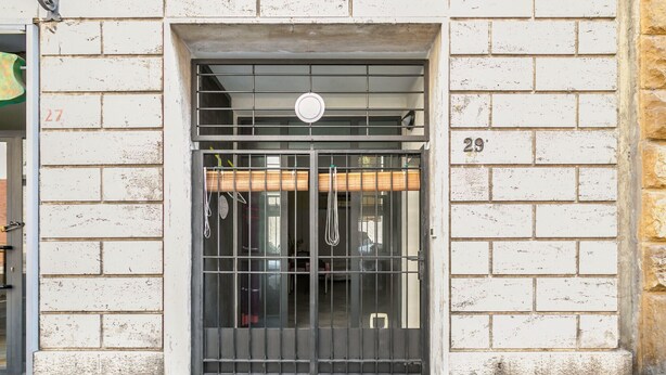 A building entrance with a metal gate, numbered 29, and a small window above the door. - Essenza Holiday House (Florencia)