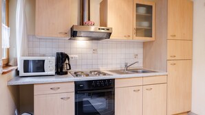 A compact kitchen with a microwave, stove, sink, and oven. - Ferienwohnung Unternberg 45qm, Terr., Küche, Behinderteng., 1 Schlafzimmer (Ruhpolding)