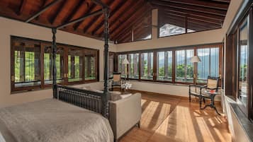 A spacious bedroom with a four-poster bed, large windows, and a view of the outdoors.