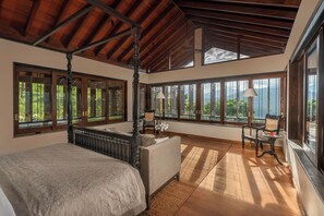 Ein geräumiges Schlafzimmer mit Himmelbett, großen Fenstern und Blick ins Freie.