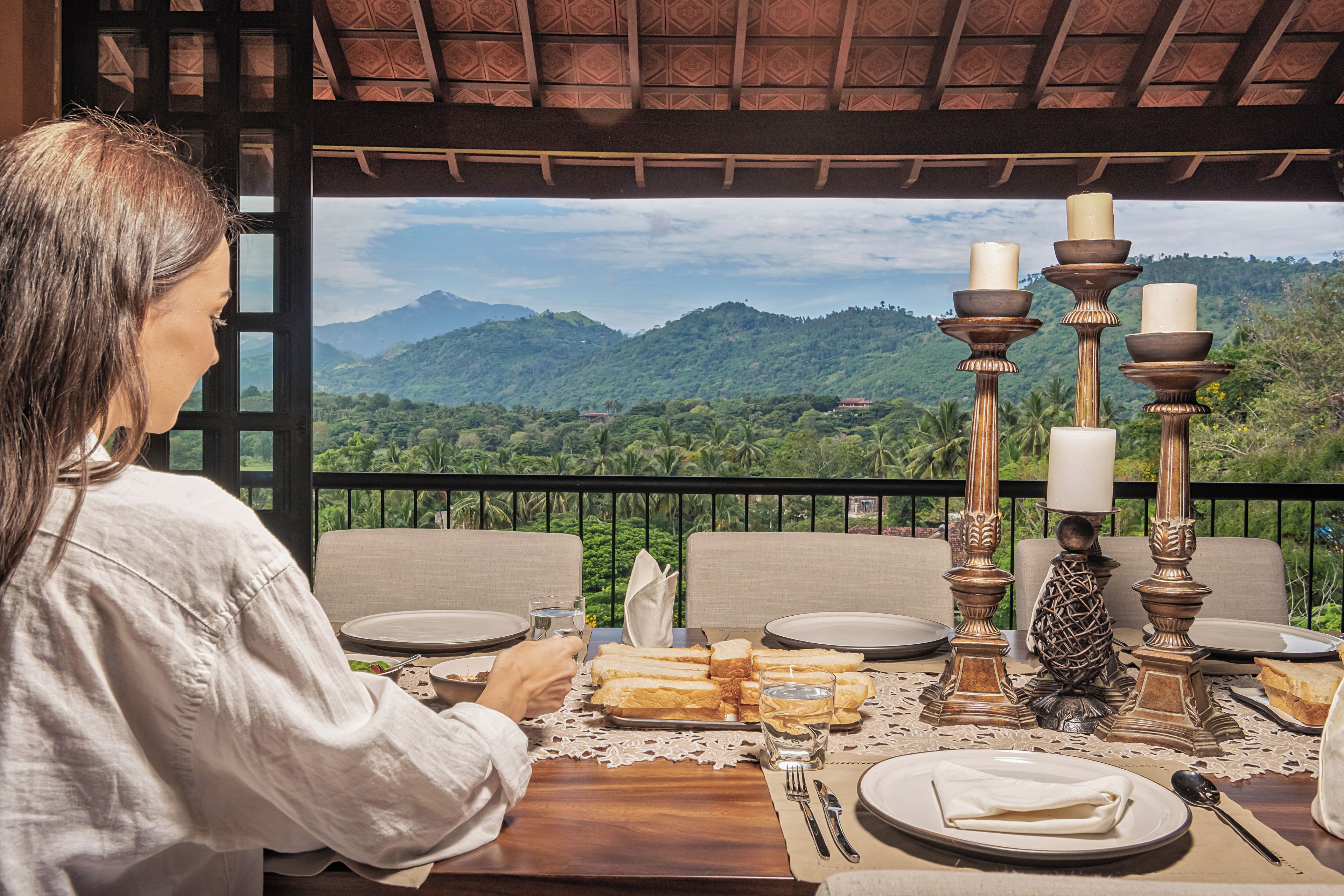 A dining table set with plates, cutlery, and bread, overlooking a mountainous landscape.