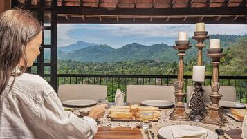A dining table set with plates, cutlery, and bread, overlooking a mountainous landscape.