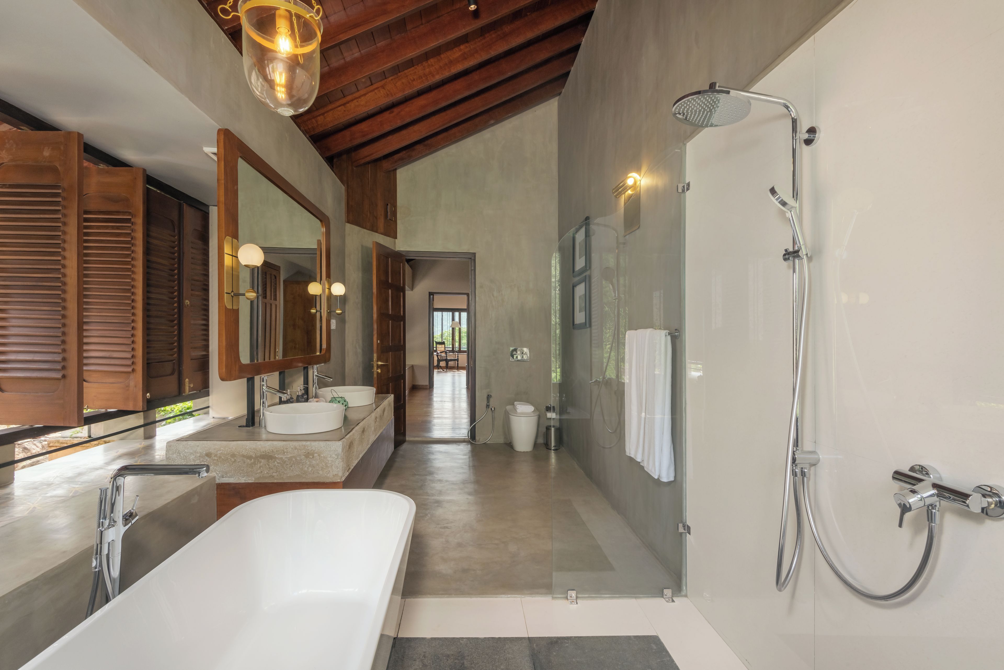 Un baño moderno con una bañera grande, dos lavamanos, una ducha a pie y techo de madera.