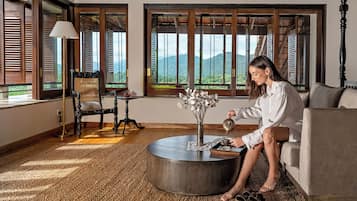 A room with a large window, a round coffee table, a chair, and a sofa.