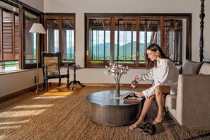 Ein Zimmer mit großem Fenster, rundem Couchtisch, einem Sessel und einer Couch.
