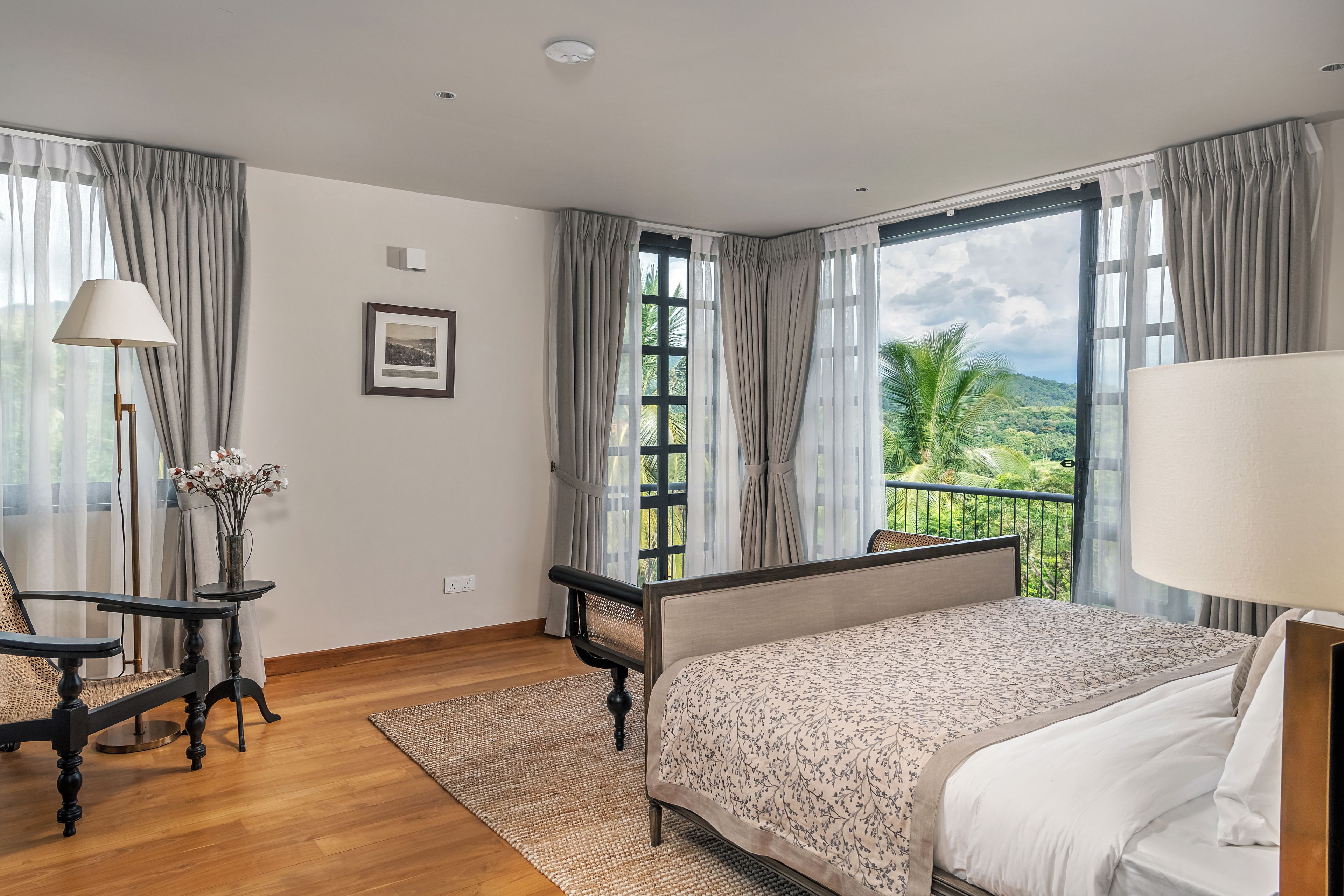 Ein Hotelzimmer mit Bett, Schreibtisch, Stuhl, einem Fenster mit Blick auf Grünflächen und einem Bild an der Wand.