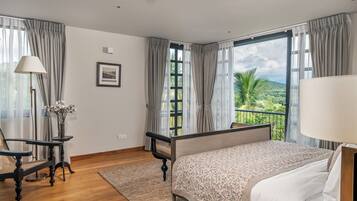 Ein Hotelzimmer mit Bett, Schreibtisch, Stuhl, einem Fenster mit Blick auf Grünflächen und einem Bild an der Wand.