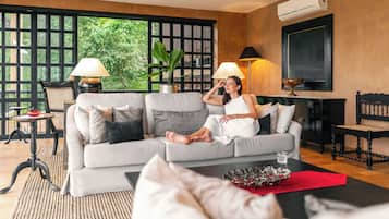 A modern living room with a sofa, a coffee table, a side table, and a potted plant.