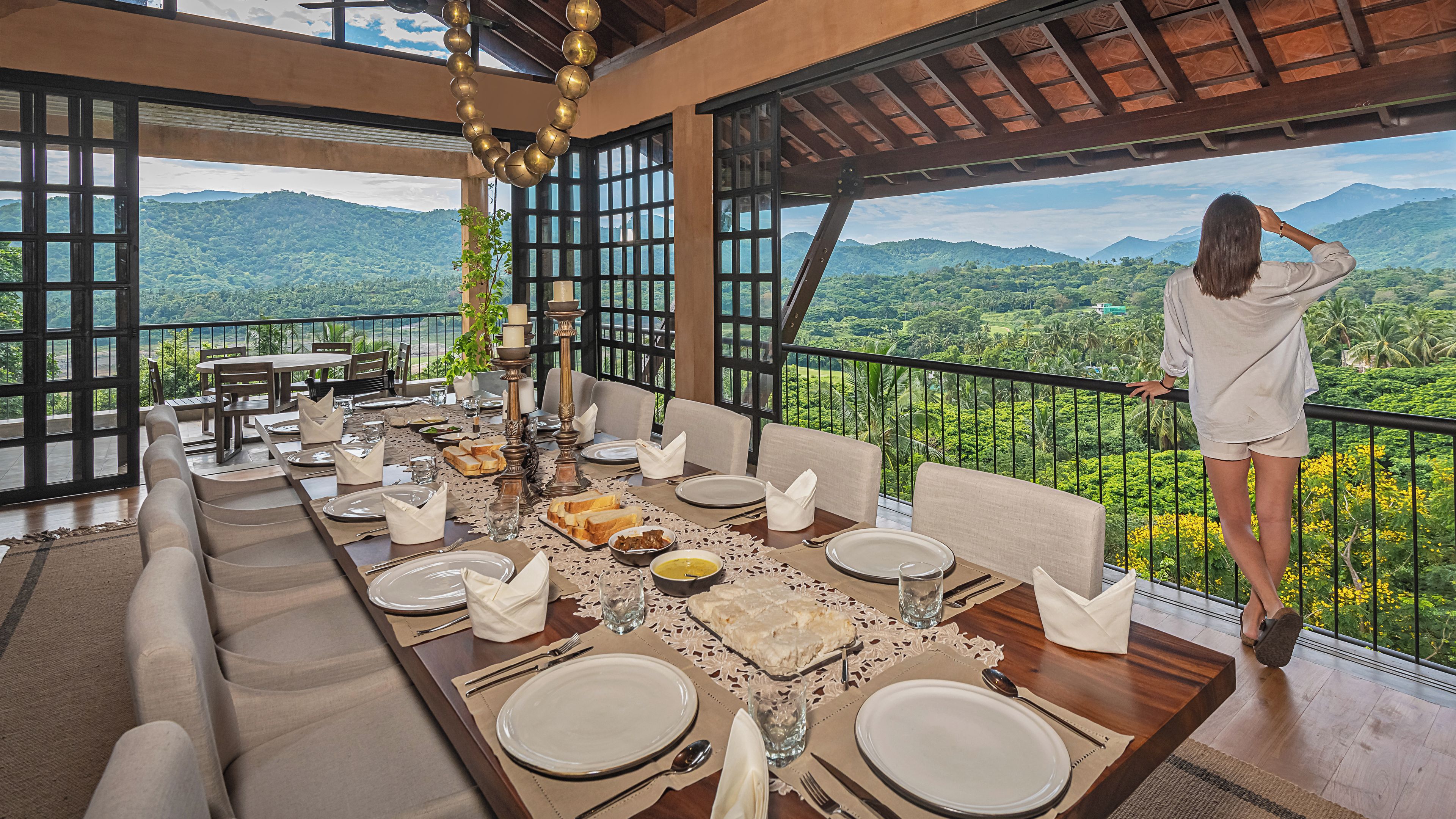 A dining area with a table set for four, overlooking a lush landscape with mountains and greenery.