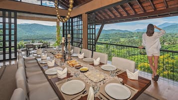 A dining area with a table set for four, overlooking a lush landscape with mountains and greenery.