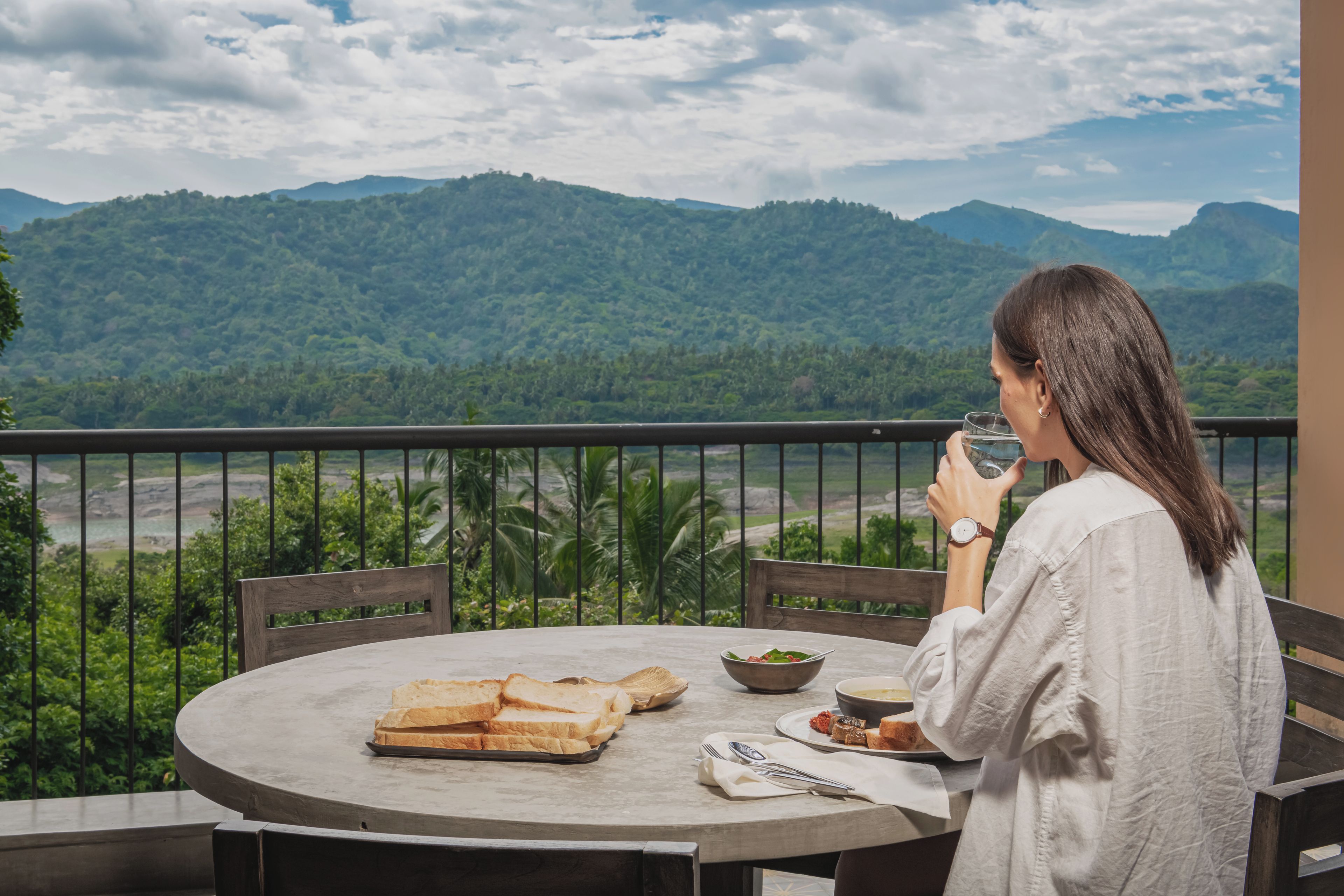 Una persona sentada a una mesa redonda con vista a un paisaje montañoso.