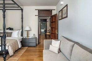 Un dormitorio con cama con dosel, mesita de noche, lámpara y vista al baño.