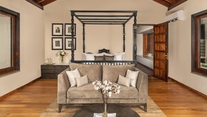 A bedroom with a four-poster bed, a sofa, and a vase of flowers.