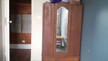 A room with a wooden wardrobe, a door leading to another room, and a blue wall.