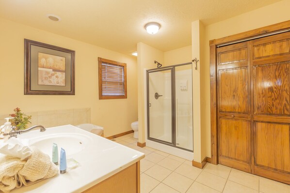 A bathroom with a sink, toilet, shower, and wooden door. - L130A 1-Bedroom Loft Lakeview Cabin (Reeds Spring)