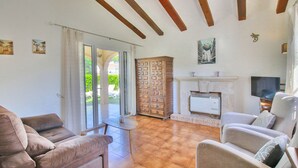 A living room with a fireplace, a television, and a view of the outdoors. - Bungalow in Denia 3 minutes from the beach with air-conditioning (Denia)
