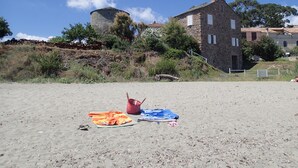 A sandy beach with a stone building and a tower in the background. - Villa Climatisée T3 Piscine Chauffée Accès Direct à la Plage de Prunete (Cervione)