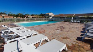 A swimming pool with white lounge chairs and a stone patio. - Villa Climatisée T3 Piscine Chauffée Accès Direct à la Plage de Prunete (Cervione)