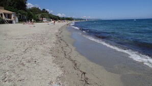 A beach with a sandy shore, a few people, and a clear sky. - Villa Climatisée T3 Piscine Chauffée Accès Direct à la Plage de Prunete (Cervione)