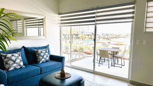 Een moderne woonkamer met een blauwe bank, een salontafel en een grote schuifpui die uitkomt op een terras.