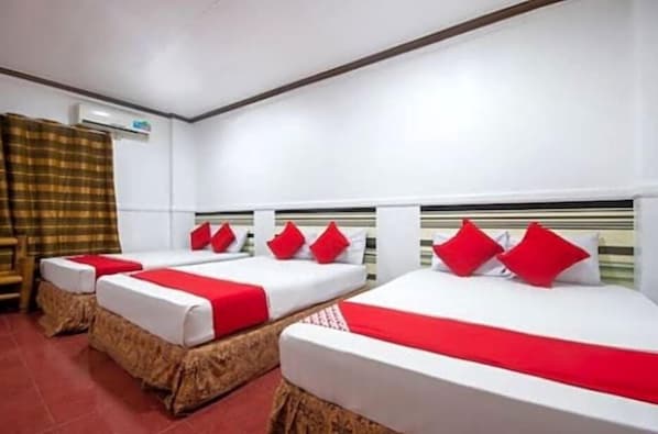 A hotel room with three beds, each with red and white bedding, and a headboard with a striped pattern. - Max Travellers Inn (Lapu-Lapu)