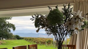 A dining table set for six with a view of a vineyard and mountains. - Ben Morven Vineyard Cottage (Fairhall)
