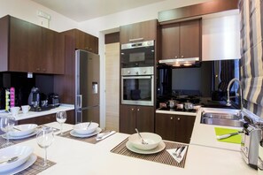 A modern kitchen with dark wood cabinets, stainless steel appliances, and a dining area set for four.