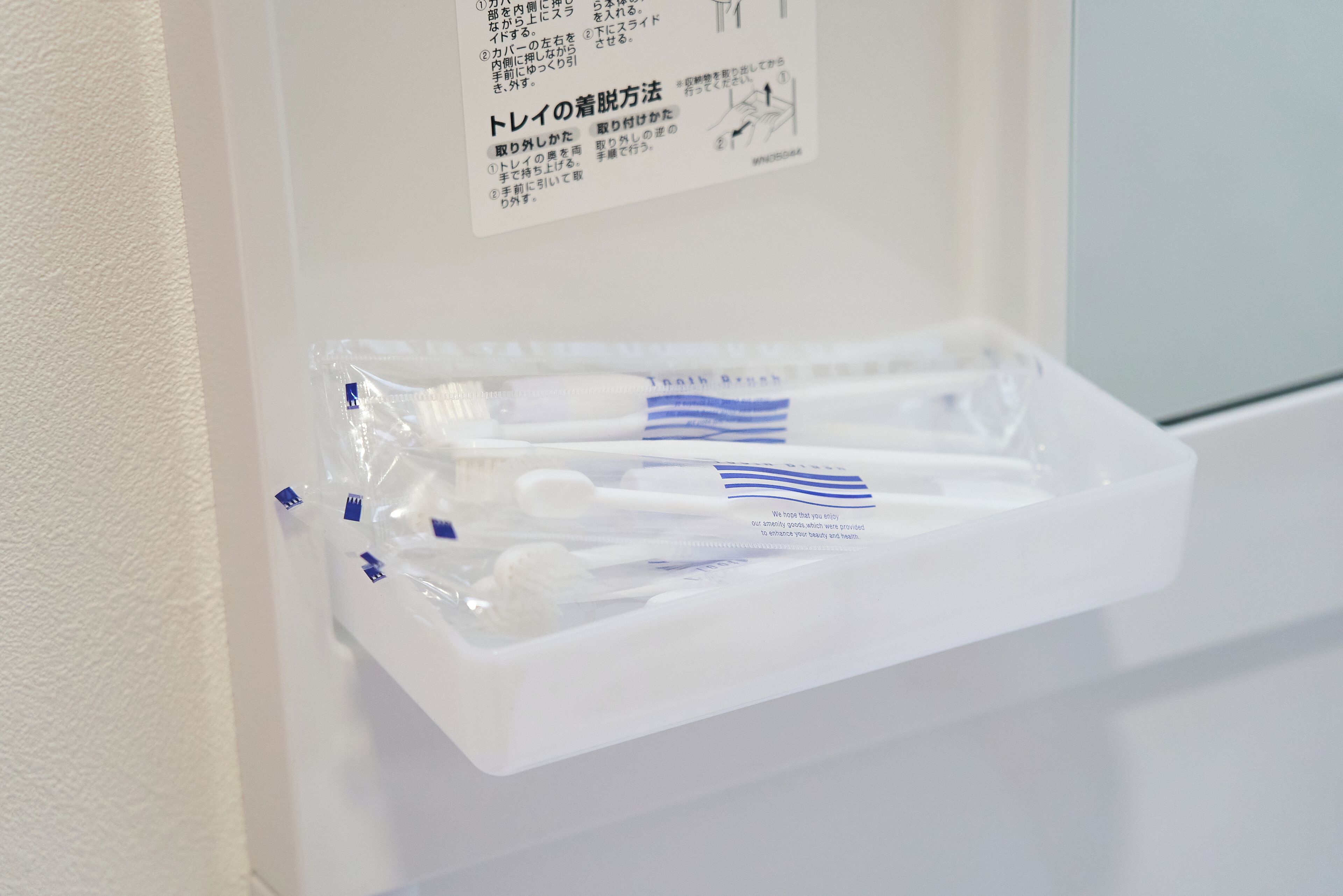 A white bathroom with a shelf holding toothbrushes and a toothbrush holder.