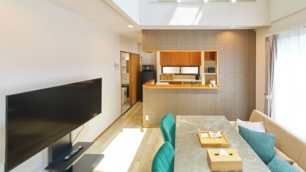 A modern living room with a flat-screen TV, a dining table with chairs, and a sofa. - The Prime TOKYO HANEDA (Tokyo)