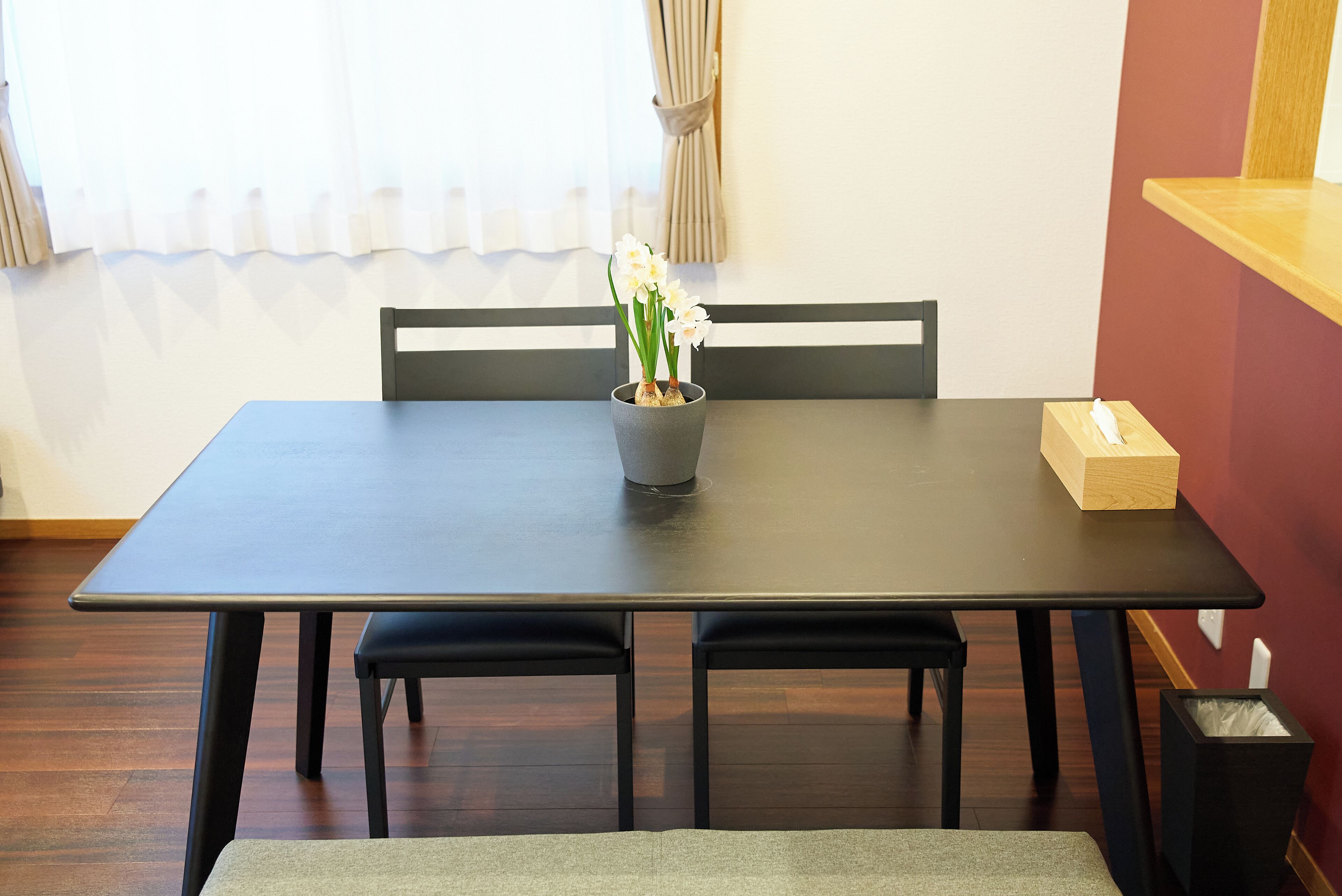 A dining table with chairs, a vase with flowers, and a tissue box.