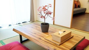 A tatami mat room with a low wooden table, a potted maple tree, and red cushions. - The Prime TOKYO HANEDA (Tokyo)