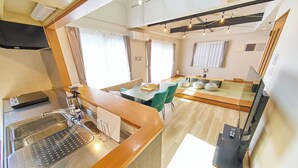 A modern kitchen with a stainless steel sink, a built-in oven, and a dining area with a table and chairs. - The Prime TOKYO HANEDA (Tokyo)