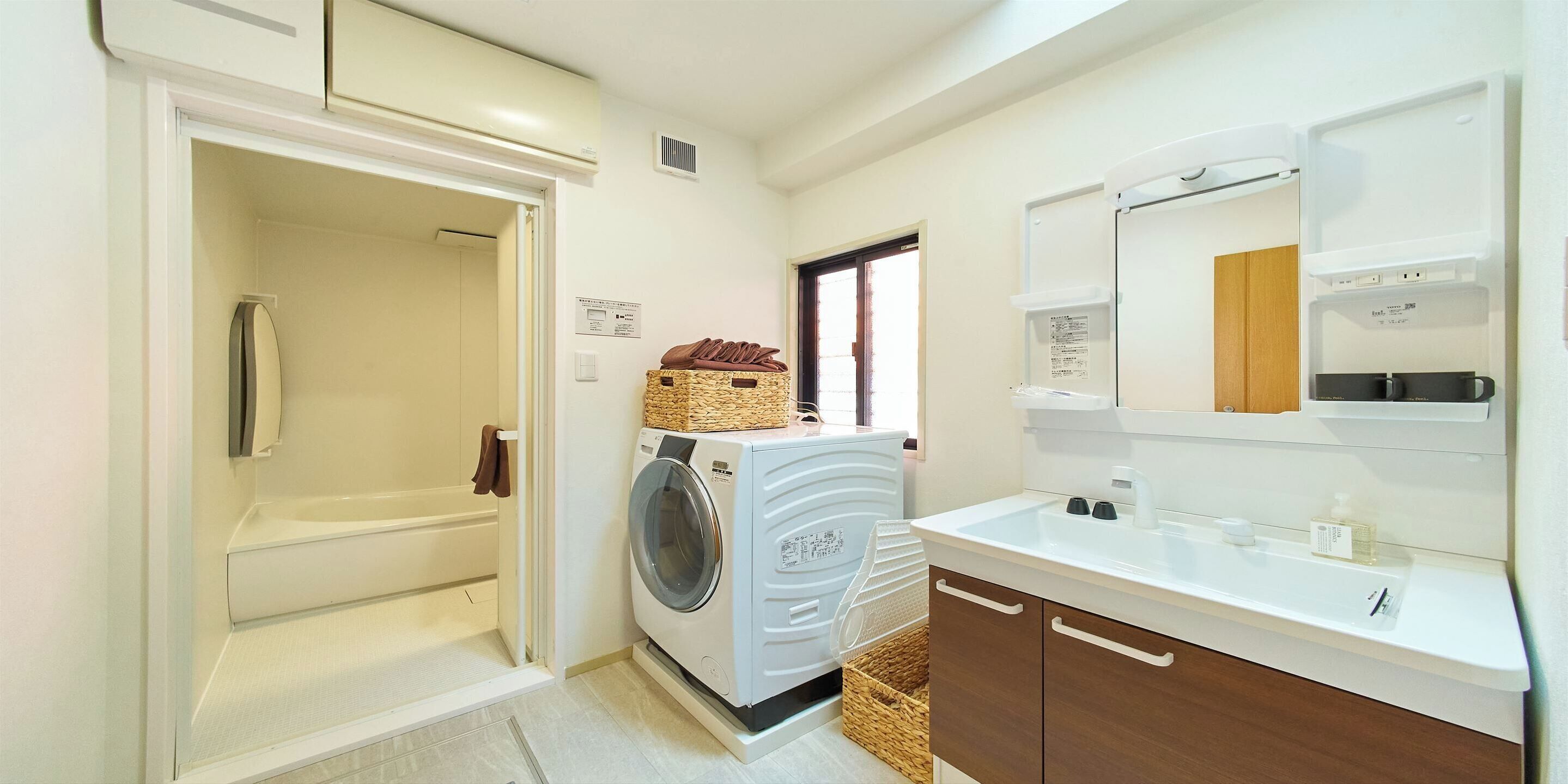 Une petite salle de bain équipée d’un lave-linge, d’un lavabo et d’un miroir.
