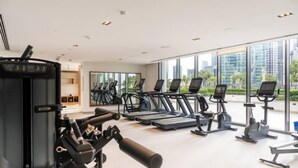 Et fitnesscenter med løbebånd, crosstrainere og styrkeløftningsudstyr.