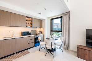 A modern kitchen with built-in appliances, a dining area with a table and chairs, and a large window with curtains.