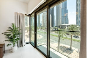 A modern room with large windows, a potted plant, and a view of a cityscape.