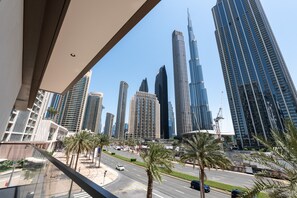 A cityscape with modern skyscrapers, including the Burj Khalifa, and a road with palm trees and vehicles.