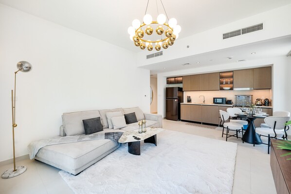 A modern living room with a sofa, coffee table, and a dining area with chairs.